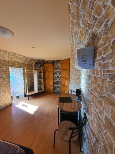 a room with a stone wall and a table and chairs at Panzio A mi Paradicsomunk in Véménd