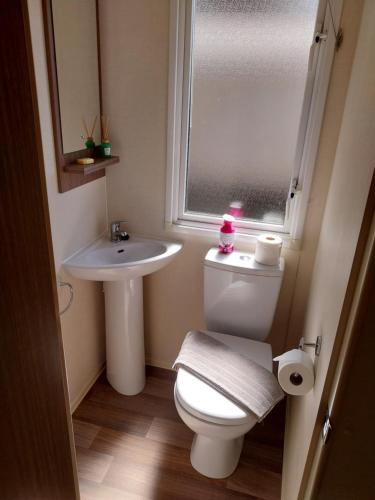 een badkamer met een toilet, een wastafel en een raam bij Family breaks at Rockley Park with Prosecco and a box of chocolates on arrival in Poole