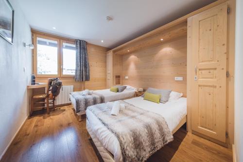 um quarto com 2 camas e uma secretária. em L'Auberge Nordique em Le Grand-Bornand