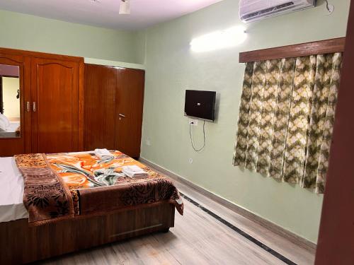 a bedroom with a bed and a tv on the wall at The City Guesthouse in Jaipur