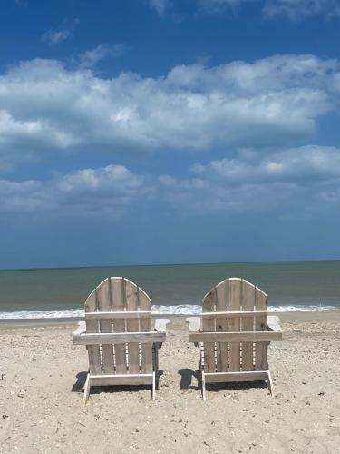 two beach chairs sitting on the sand at the beach at Aiwa Hotel in Mayapo