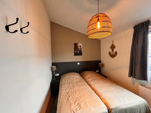een slaapkamer met een bed en een kroonluchter bij Exclusieve vakantievilla ***** Markermeer in Bovenkarspel
