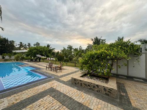 - une piscine avec une table, des chaises et des arbres dans l'établissement Shades Hotel & Villa, à Matara