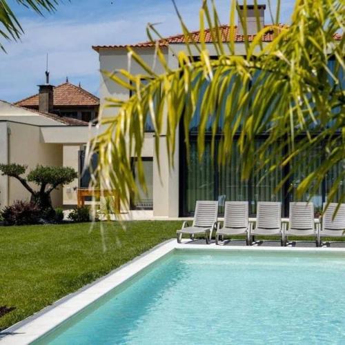 a swimming pool with chairs and a house at Celeiro do Carvalho in Estela