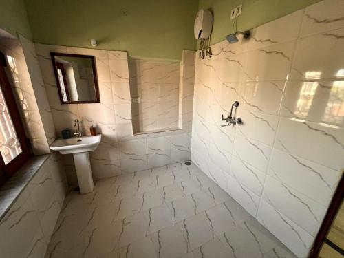a white bathroom with a sink and a shower at The City Guesthouse in Jaipur