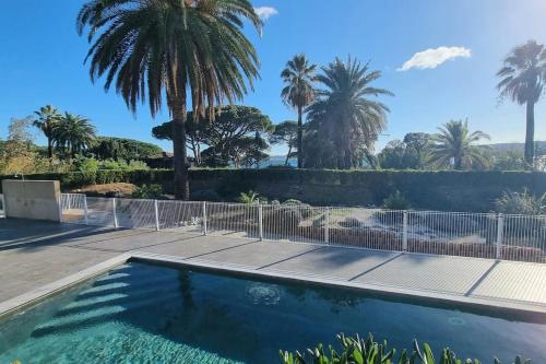 une piscine avec une clôture et des palmiers dans l'établissement Chez K&D Appartement, piscine, mer 150m, à Grimaud