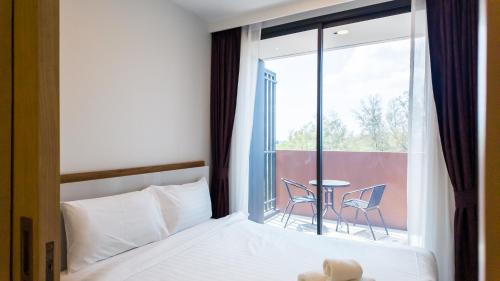 een slaapkamer met een bed en een raam met een tafel bij Апартаменты в Лагуне SkyPark c видом на гольф поле in Bang Tao Beach