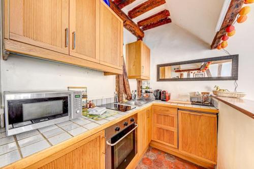 - une cuisine avec des placards en bois et un four micro-ondes dans l'établissement Appartement charmant, atypique et central !, à Paris