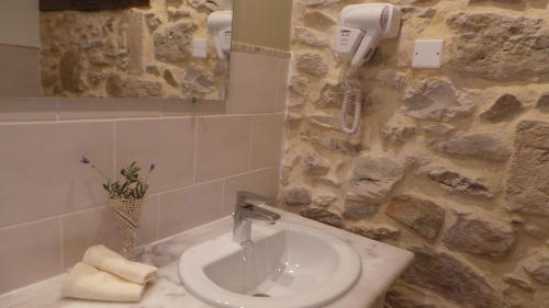 uma casa de banho com um lavatório e uma parede de pedra em Le Mas Des Ferrayes em Ongles