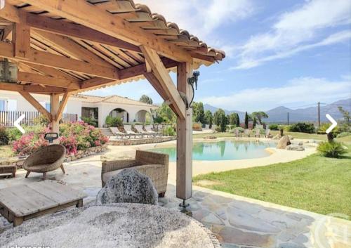 une terrasse avec une pergola en bois et une piscine dans l'établissement VILLA luxueuse privée avec piscine lagon, à Calenzana