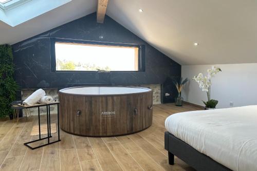 a bedroom with a large wooden tub in a room with a bed at La Love Room de St Nazaire les Eymes in Biviers