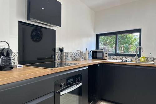 a kitchen with black cabinets and a counter top at La Love Room de St Nazaire les Eymes in Biviers