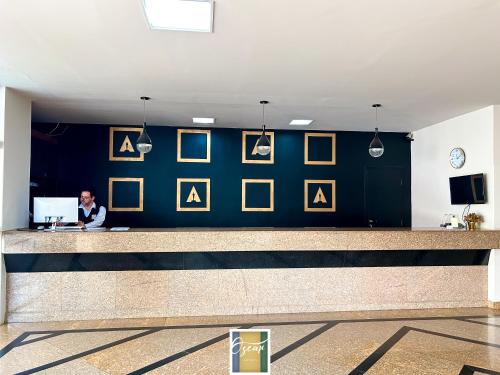 mężczyzna siedzący przy ladzie w biurze w obiekcie HOTEL OSCAR GOLD w mieście Montes Claros