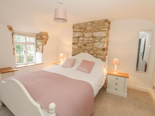 ein Schlafzimmer mit einem großen Bett und einer Steinwand in der Unterkunft Norden Cottage in Weymouth