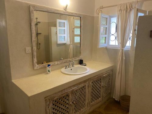 łazienka z umywalką, lustrem i oknem w obiekcie Fulvia House w mieście Malindi