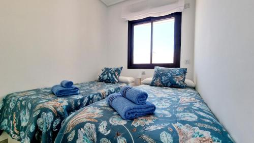 twee bedden in een kamer met blauwe handdoeken erop bij Apartament Porto Marina in Torre de la Horadada