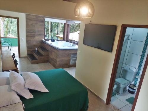 a bedroom with a bathroom with a tub and a television at Pousada Aquarela - Macacos in Macacos