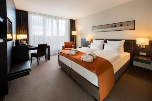 a hotel room with a large bed and a desk at ATLANTIC Hotel Lübeck in Lübeck