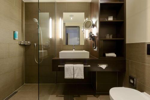 a bathroom with a sink and a shower at ATLANTIC Hotel Lübeck in Lübeck