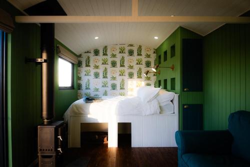 a green bedroom with a bed and a fireplace at Gooseberry Shepherds Hut in Worcester