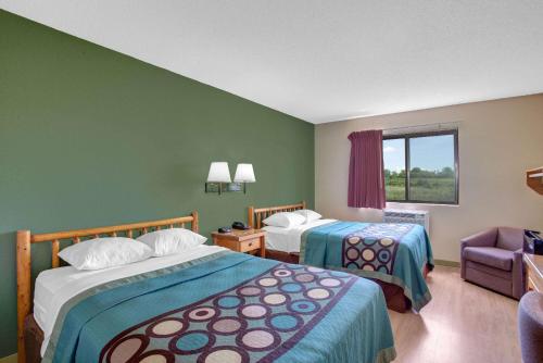 a hotel room with two beds and a chair at Super 8 by Wyndham Ticonderoga in Ticonderoga