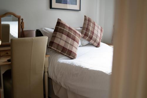 a bed with two plaid pillows on top of it at The Ship Inn in Holy Island