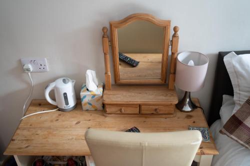 a wooden dressing table with a mirror and a chair at The Ship Inn in Holy Island
