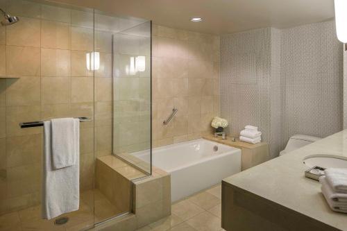 a bathroom with a shower and a tub and a sink at Manchester Grand Hyatt San Diego in San Diego