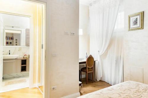 a white bedroom with a sink and a desk with a mirror at Menotti elegant Apartment in Rome