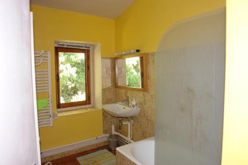 Baño amarillo con lavabo y ventana en Chambre dans maison de caractère, en Nimes