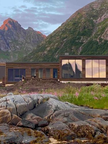 a house in the mountains with a large rock at New lodge at seaside, near Henningsvær Lofoten in Kleppstad