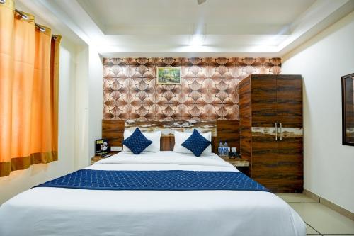 ein Schlafzimmer mit einem großen weißen Bett mit blauen Kissen in der Unterkunft Grand Empire Suites By Delhi Airport in Neu-Delhi