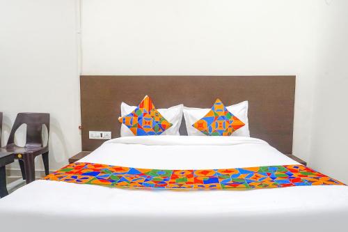 a white bed with colorful sheets and pillows on it at FabHotel Om Sai in Nashik