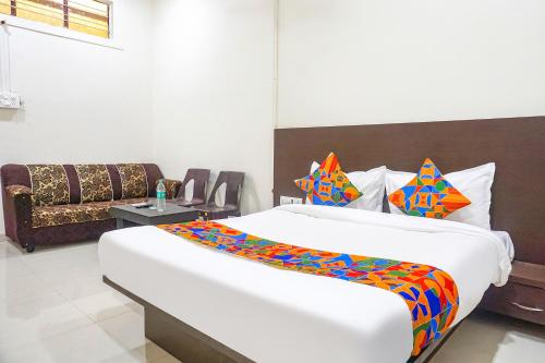 sypialnia z dużym białym łóżkiem z kolorowymi poduszkami w obiekcie FabHotel Om Sai w mieście Nashik