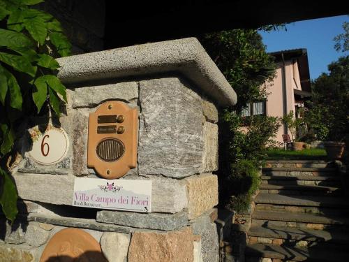 a stone bird house with a sign on it at Villa Campo dei Fiori in Casciago