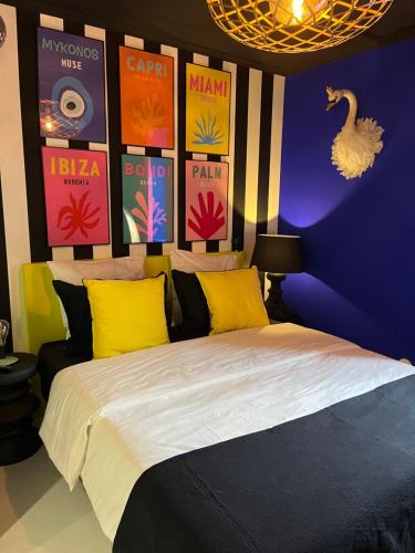 - une chambre dotée d'un lit avec des oreillers jaunes et d'un mur avec des affiches dans l'établissement Appartement avec Jacuzzi pour 2 personnes, à Villefranche-sur-Saône