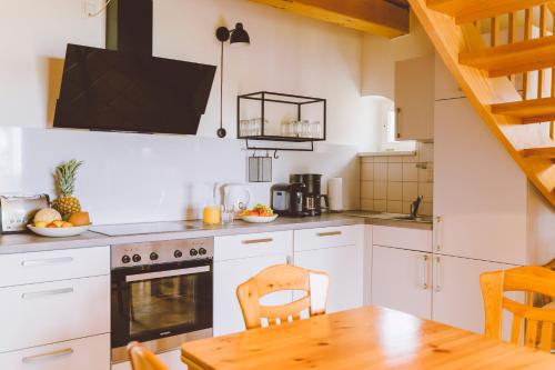a kitchen with white cabinets and a wooden table at Gut Oehe in Maasholm