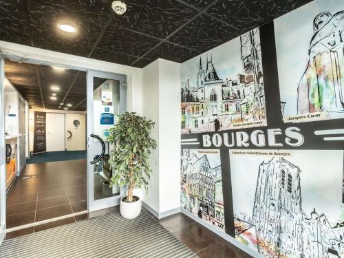 a lobby of a building with posters on the walls at ibis budget Bourges in Bourges