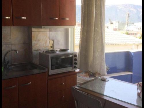 a kitchen with a microwave and a sink and a window at Igoumenitsa heart flats to let Mariasroom studios appart seaside-city Spyropoulos in Igoumenitsa