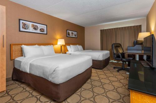 a hotel room with two beds and a desk at Comfort Inn Laval in Laval