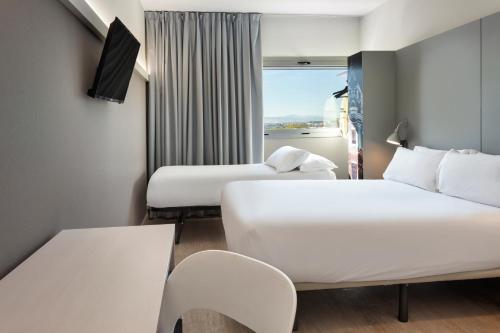 a hotel room with two beds and a window at B&B HOTEL Valencia Aeropuerto in Paterna