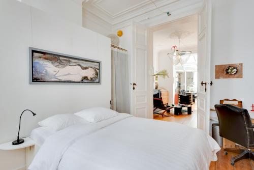 een witte slaapkamer met een bed en een stoel bij Saint Catherine Art Residence in Brussel