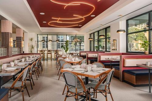 a restaurant with tables and chairs and windows at Origin Baton Rouge, a Wyndham hotel in Baton Rouge