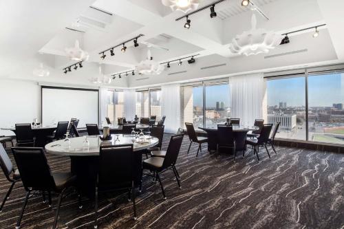 a dining room with tables and chairs and large windows at Lorenzo Hotel Dallas, Tapestry Collection by Hilton in Dallas