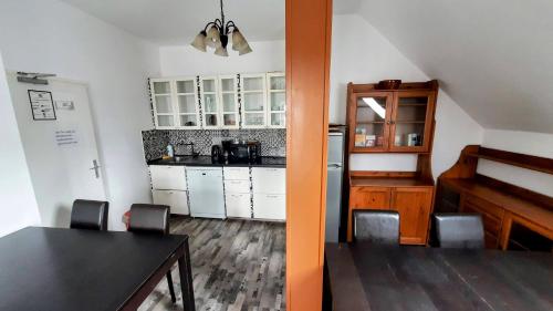 une cuisine avec des placards blancs, une table et une salle à manger dans l'établissement Am Lindenhof - Self Check-In Hotel, à Hanovre