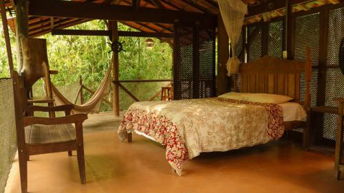 um quarto com uma cama e uma cadeira em Cabana do Tarzan na Praia de Parati Mirim em Paraty