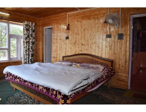 een slaapkamer met een bed in een houten kamer bij Pine View Resort, Pahalgam in Pahalgām