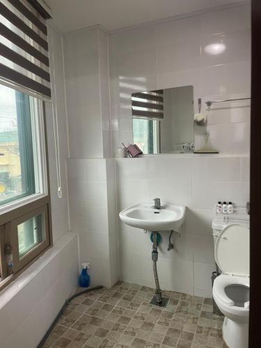 a white bathroom with a toilet and a sink at Stay SonSu in Jeju