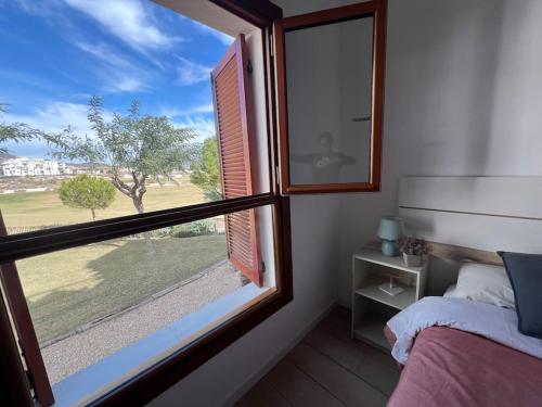 1 dormitorio con ventana y vistas a un árbol en Inmejorable Aptmto. vistas directas golf El Valle Golf, en Baños y Mendigo