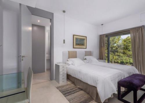 a white bedroom with a large bed and a window at Olivo - Sol de Mallorca in Sol de Mallorca